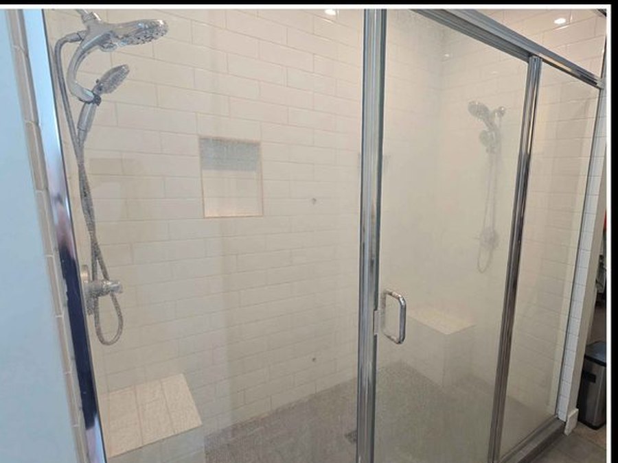 Glass shower enclosure, hard-water film and soap scum removed — before