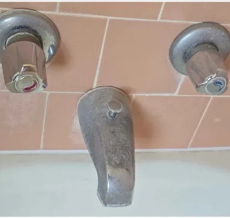 Tub faucet and handles, mineral buildup removed — before